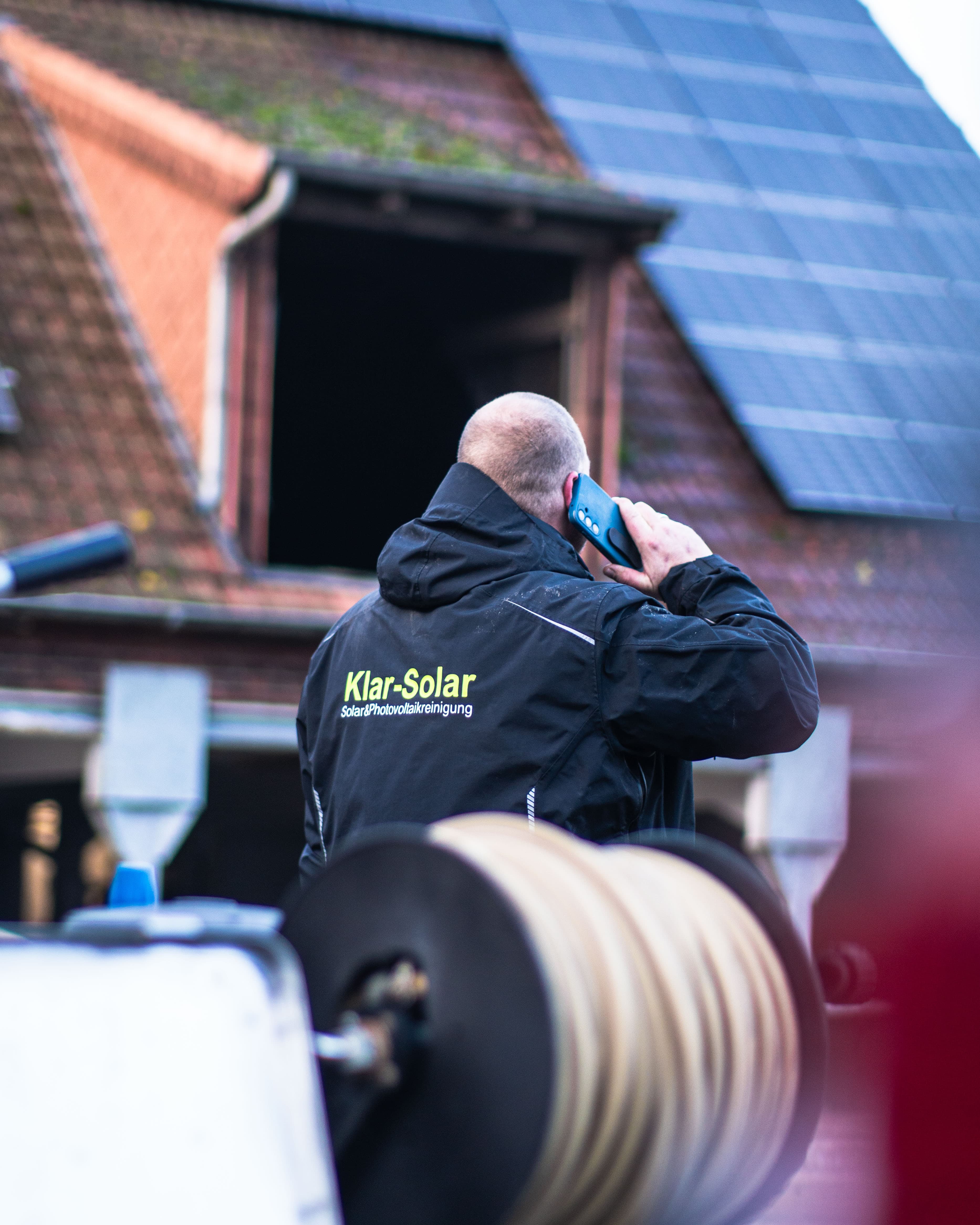 KlarSolar Mitarbeiter telefoniert vor Solaranlage